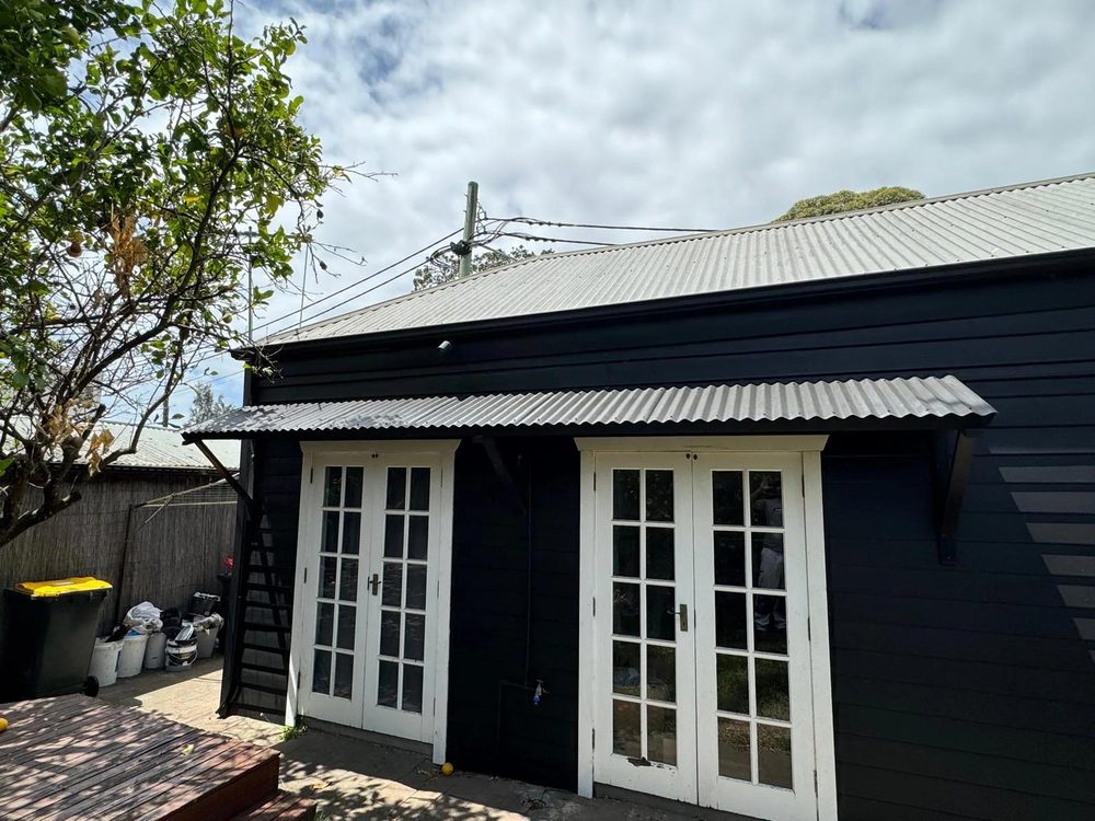 Black weatherboard studio with freshly painted white French doors